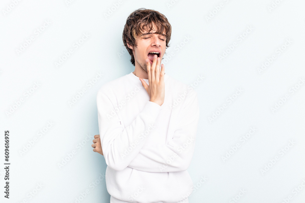 Young caucasian man isolated on blue background yawning showing a tired gesture covering mouth with hand. Young caucasian man isolated on blue background yawning showing a tired gesture covering mouth with hand.