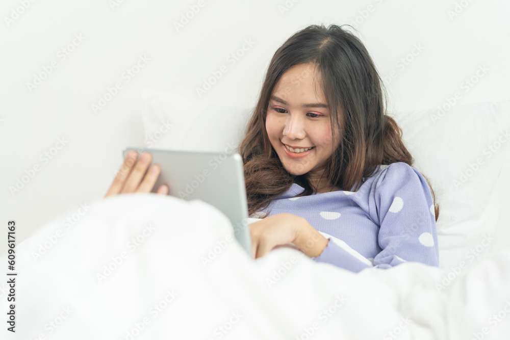 Asian woman watching movie in tablet on the bed at home Asian woman watching movie in tablet on the bed at home