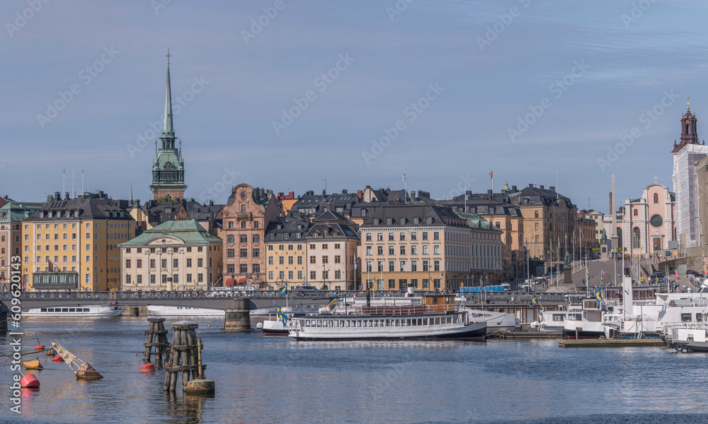 Boats moored at the jetties at the bridge Skeppsholmsbron, the old town Gamla Stan in the background, a sunny summer day in Stockholm