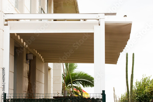 Attached pergola on a villa in Spain. A modern or classic hotel on the tropical resort. White wooden long courtyard canopy over house entrance, cottage. Front door canopies. photo