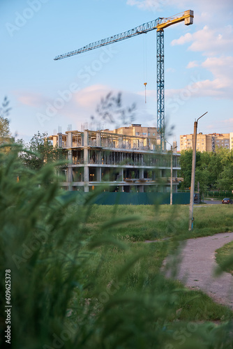 Construction crane against the sky. Construction site. Vertical photo. Sunset.