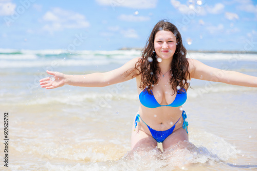 海辺でカメラに向かって水をかける水着のセクシーな女の子