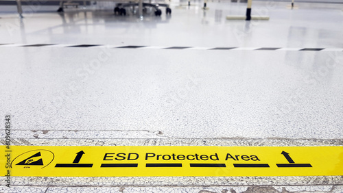 On a floor of the electronics manufacturing covered industrial linoleum pastes a yellow tape with a standard warning text: 