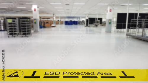 On a floor of the electronics manufacturing covered industrial linoleum pastes a yellow tape with a standard warning text: 