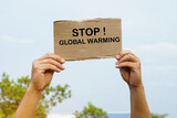 Close up hands hold paper card with word STOP! GLOBAL WARMING. Concept, campaign people around the world to stop activities that can cause global warming. Environment conservation.    