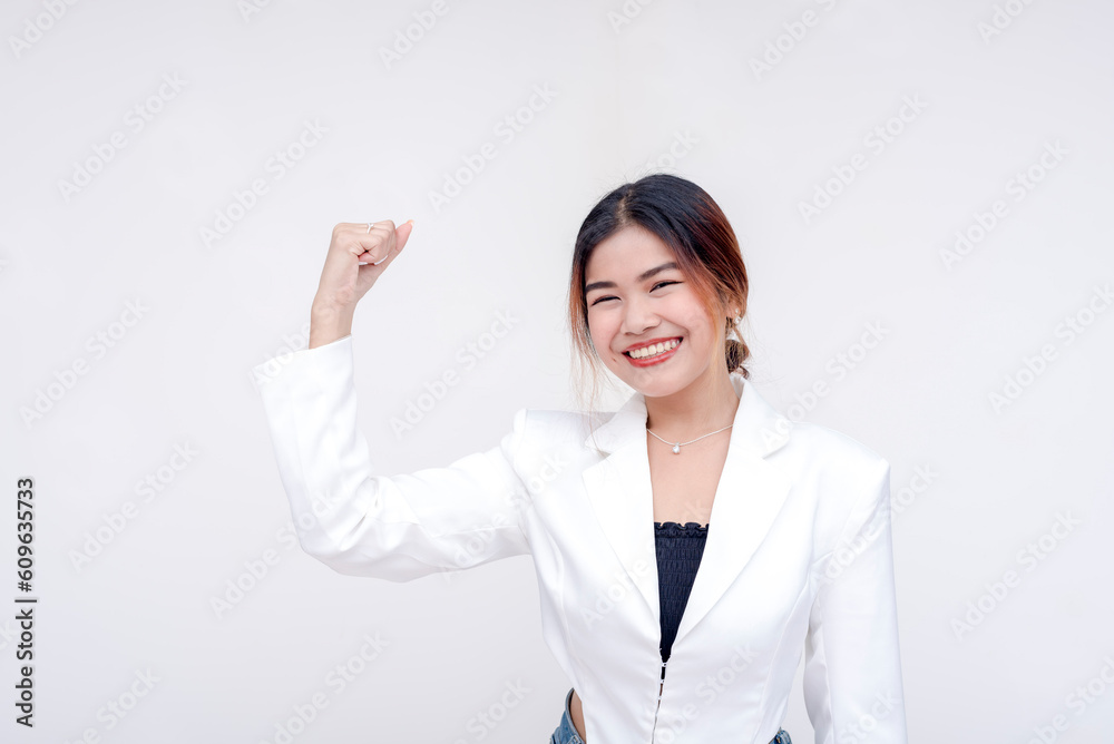 A cheerful young woman with her left arm raising up showing power and strength. Isolated in a white background. A cheerful young woman with her left arm raising up showing power and strength. Isolated in a white background.