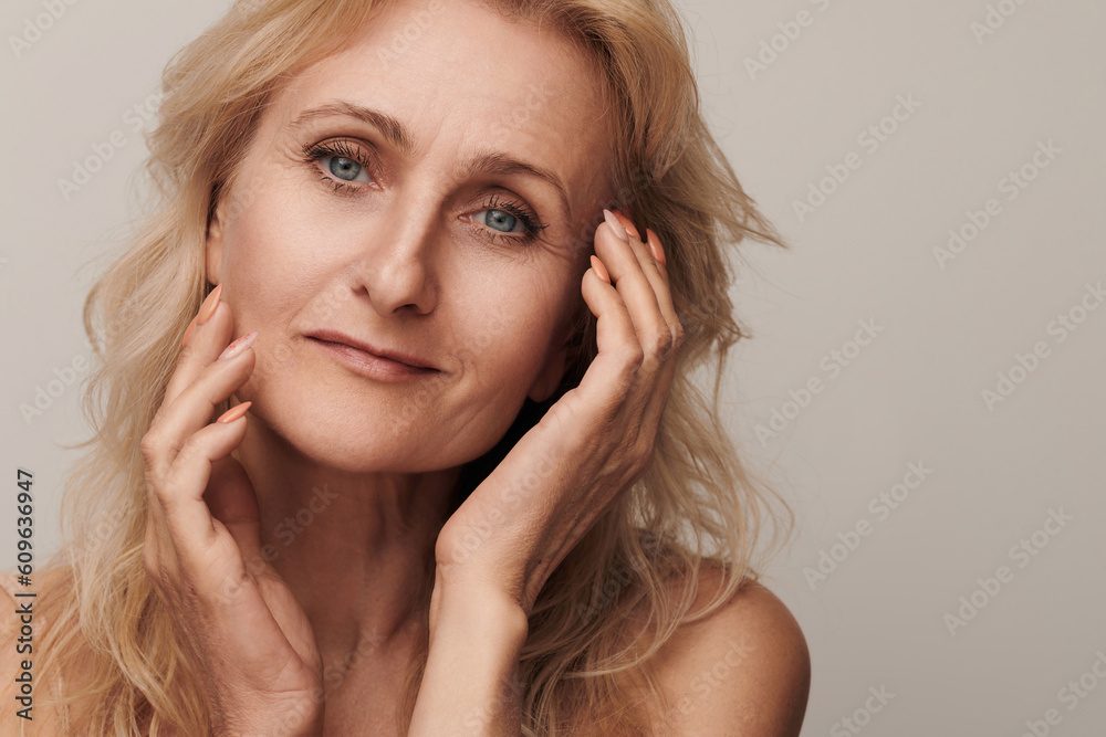Beautiful blond middle aged woman smiling looking camera touching face portrait. Elegant mature lady no makeup 50 years old close-up isolated on white studio. Women's health, cosmetology, skin care Beautiful blond middle aged woman smiling looking camera touching face portrait. Elegant mature lady no makeup 50 years old close-up isolated on white studio. Women's health, cosmetology, skin care