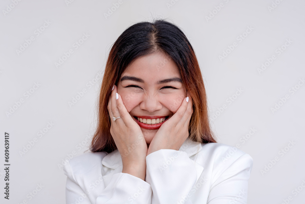 A happy and flattered young woman holding her face with both hands in joy. Isolated on a white background. A happy and flattered young woman holding her face with both hands in joy. Isolated on a white background.