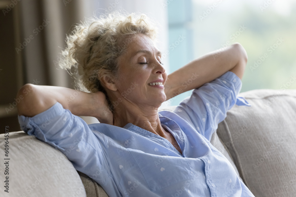 Happy peaceful lazy beautiful senior woman relaxing at home, leaning back on sofa, sitting on couch with closed eyes, open arms, breathing fresh air, smiling, enjoying leisure, relaxation Happy peaceful lazy beautiful senior woman relaxing at home, leaning back on sofa, sitting on couch with closed eyes, open arms, breathing fresh air, smiling, enjoying leisure, relaxation
