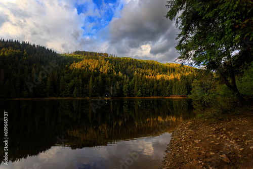 Majestic mountain lake surrounded by verdant woods and towering peaks, tranquil twilight