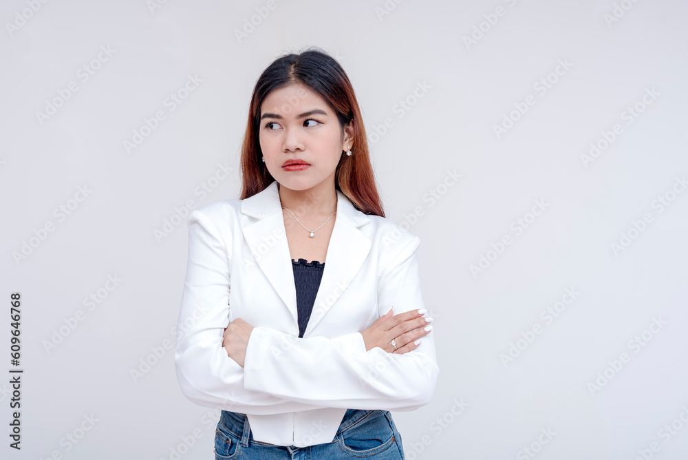 An irked and irritable young woman glancing at her left with arms crossed. Isolated on a white background. An irked and irritable young woman glancing at her left with arms crossed. Isolated on a white background.