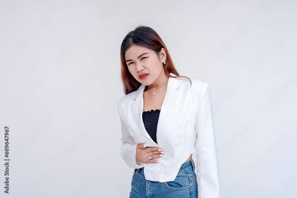 A sick young woman holding having a stomachache and holding her stomach in discomfort. Isolated on a white background. A sick young woman holding having a stomachache and holding her stomach in discomfort. Isolated on a white background.