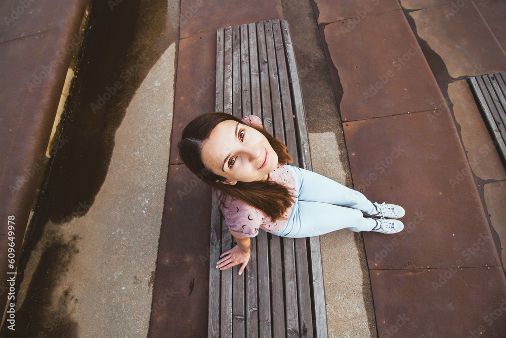 Overhead portrait of cute young woman sitting on steps and looking at camera