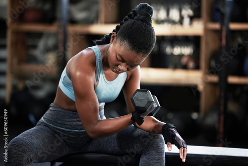 Gym  dumbbell or strong girl training  exercise or workout for powerful arms or muscles for body fitness. Concentration curls  strength or African woman athlete lifting weights or exercising biceps