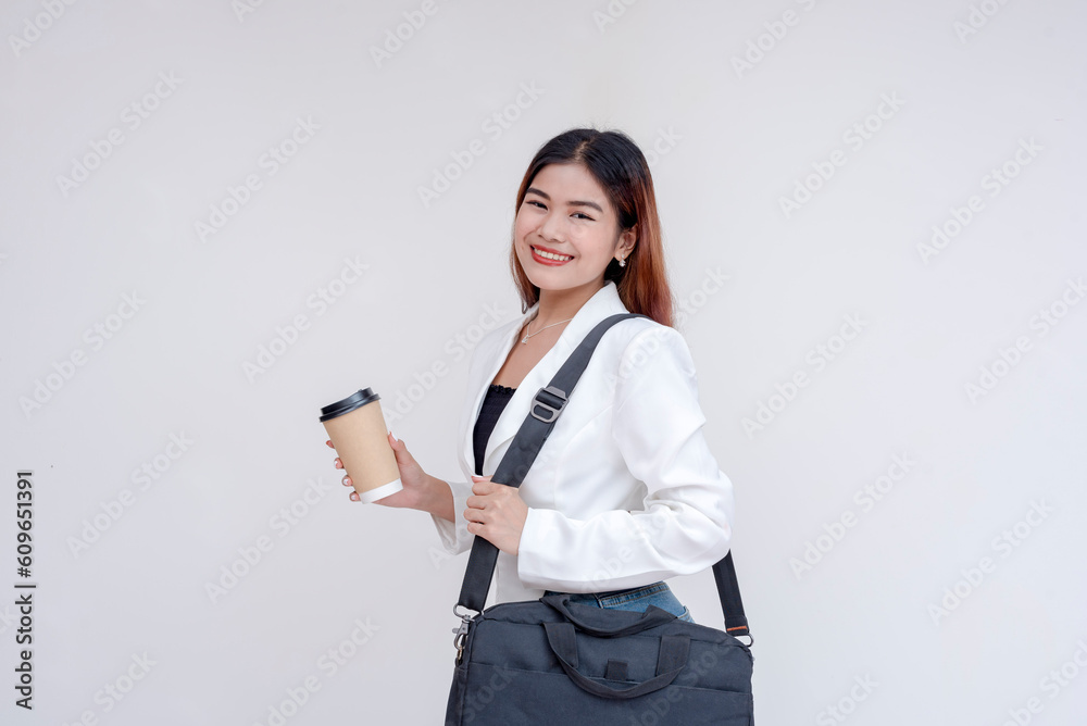 A smiling young woman with messenger bag and holding to-go coffee cup posing in front of the camera. Isolated on a white background. A smiling young woman with messenger bag and holding to-go coffee cup posing in front of the camera. Isolated on a white background.