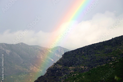 Beautiful rainbow over the mountain and gray sky.