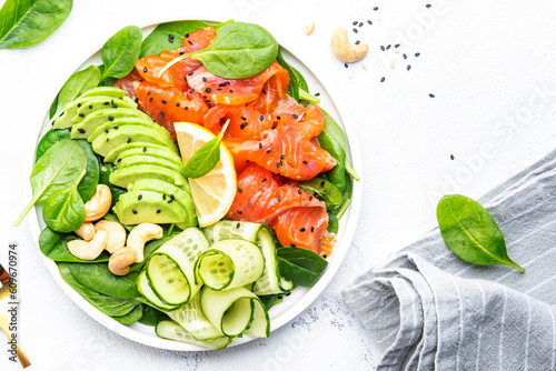 Keto salad with salmon, avocado, spinach, cucumber, sesame seeds and cashew nuts. Low-carbohydrate breakfast rich in healthy fats. White table background, top view