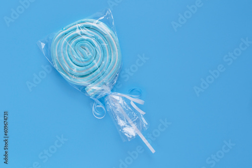 Candy on a stick. Spiral sweets.  Blue candies on a blue background. Candies in plastic packaging.