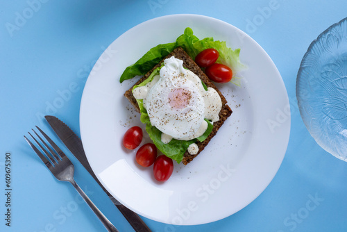poached eggs on a blue background. delicious breakfast sandwich with salad and egg. Delicious breakfast on bright blue background.