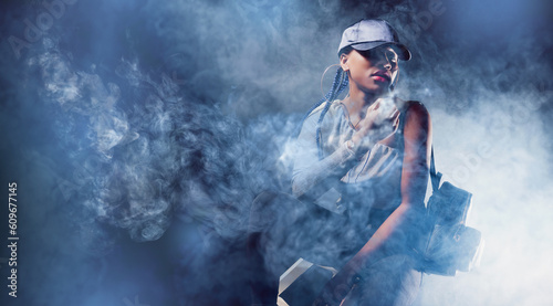 Woman in smoke. Young hipster girl. African American woman in fashionable clothes. Student girl with book and backpack. African American female student looking at camera. Woman in cap stands in smoke