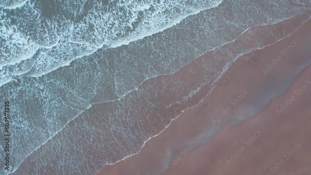 4K top down aerial shot of ocean waves crashing on the sandy beach in Mandvi, Kutch, India. Summer vacation tropical background. Still shot of ocean waves. 