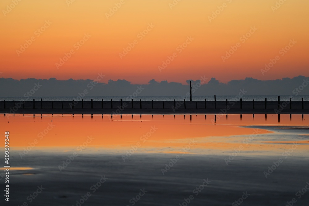 Obraz premium Pfähle spiegeln sich im Wasser bei Sonnenuntergang