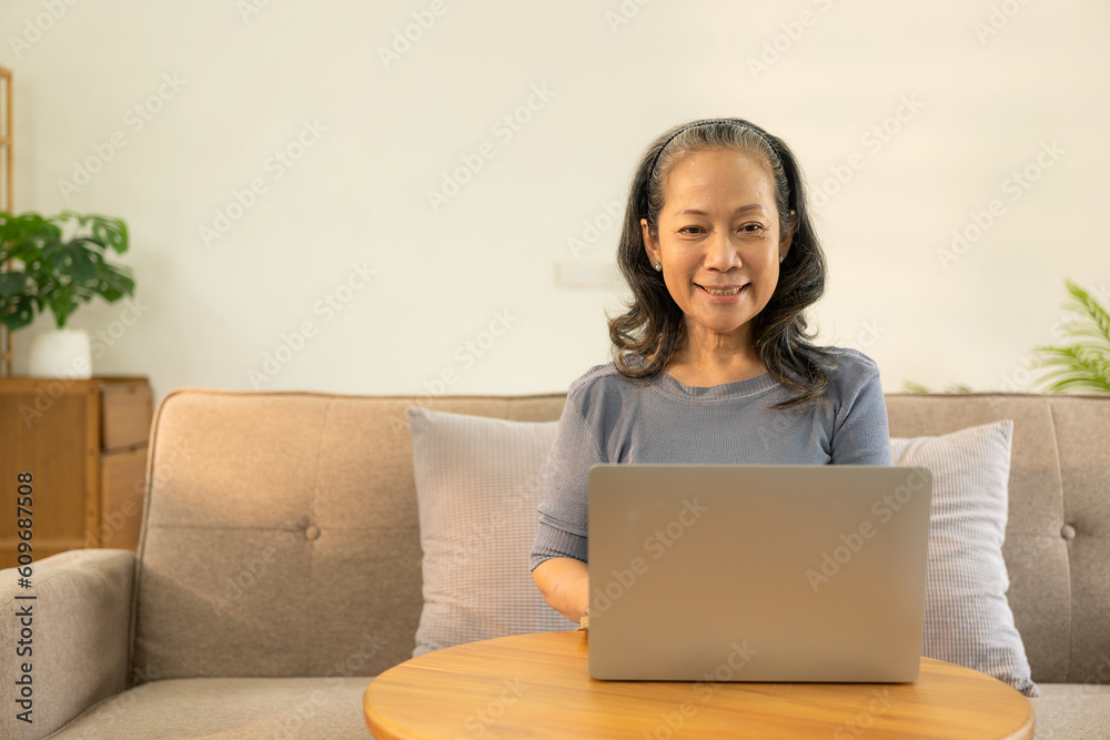 An old businesswoman in her sixties sitting at a table using a laptop. middle aged woman working at home Meet and chat online using the internet on social media. An old businesswoman in her sixties sitting at a table using a laptop. middle aged woman working at home Meet and chat online using the internet on social media.