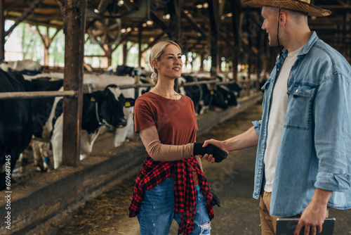 Farmer shakes hands with a female farmer in a stable.