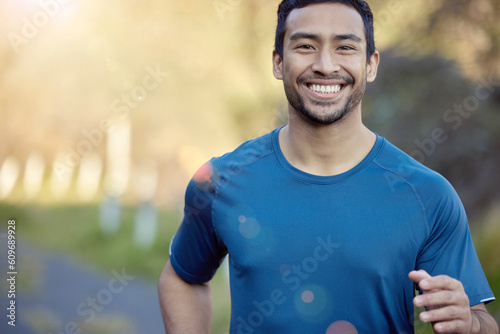 Man, smile in portrait and running outdoor, fitness and cardio with marathon, sports and athlete in nature. Asian male runner, happy with bokeh, exercise and training for race with mockup space