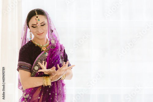 Pregnant woman in purple sari. mehendi. Indian painting on woman's hands and pregnant belly with henna tattoo on white room background