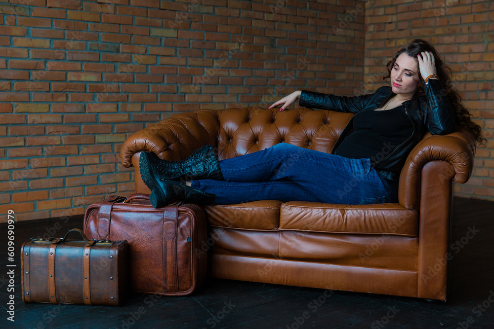 Full body of smiling pregnant woman in casual wear comfortably sitting on sofa at home Full body of smiling pregnant woman in casual wear comfortably sitting on sofa at home