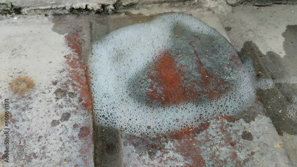 Agua con jabón  formándose con abundante espuma  en el piso de cemento.