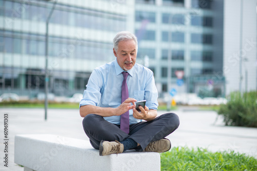 Mature businessman using his smartphone outdoor photo