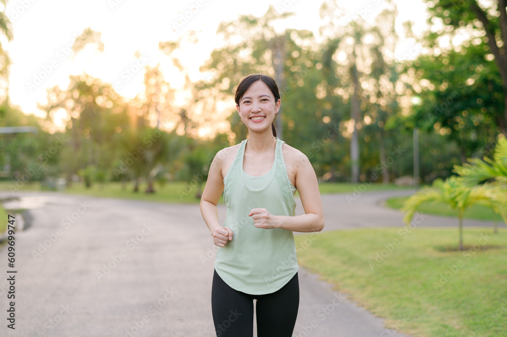 Fit Asian young woman jogging in park smiling happy running and enjoying a healthy outdoor lifestyle. Female jogger. Fitness runner girl in public park. healthy lifestyle and wellness being concept Fit Asian young woman jogging in park smiling happy running and enjoying a healthy outdoor lifestyle. Female jogger. Fitness runner girl in public park. healthy lifestyle and wellness being concept