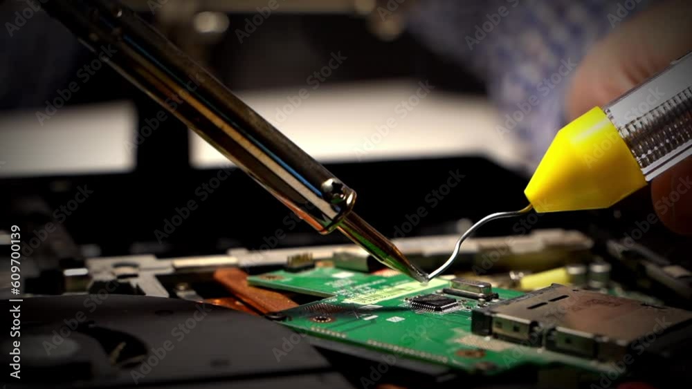 a man is soldering in a repair shop. repair of the board with a soldering iron a man is soldering in a repair shop. repair of the board with a soldering iron