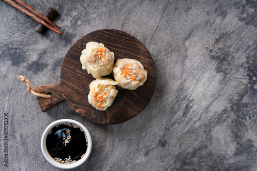 Chinese steamed dumplings or Dim Sum in bamboo steamer on dark abstract background © ILHAM_PS