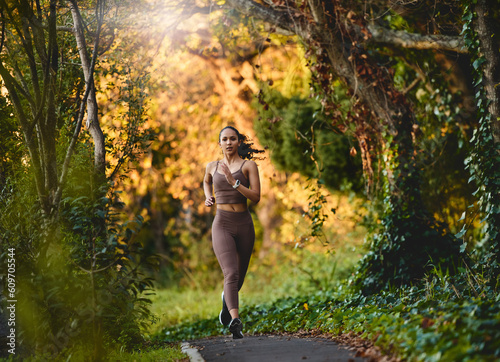 Woman, fitness and running in forest for cardio exercise, workout or training in the nature outdoors. Female person, athlete or runner exercising for healthy wellness, marathon or run in the woods