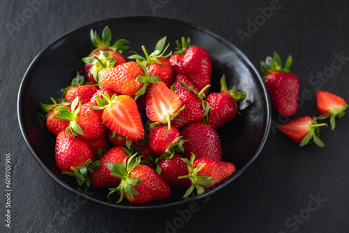 Ripe fresh strawberry in bowl on dark stone table close-up with copy space