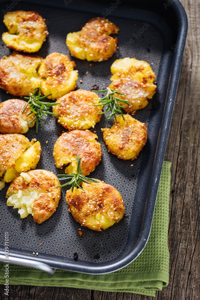 Baked potatoes in metal tray seasoned with rosemary and salt and pepper. Golden and crispy. Baked potatoes in metal tray seasoned with rosemary and salt and pepper. Golden and crispy.