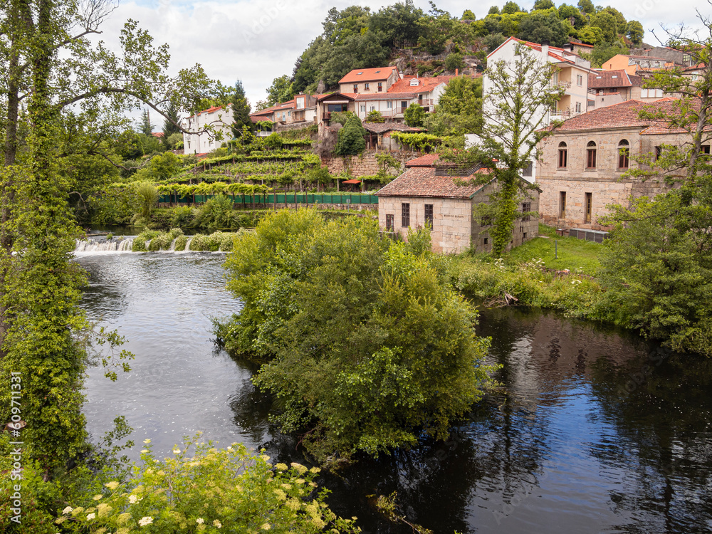 Vistas del río con casas reflejadas en la orilla rodeado de naturaleza verde en el pueblo de Allaritz, Orense, verano de 2021 España.