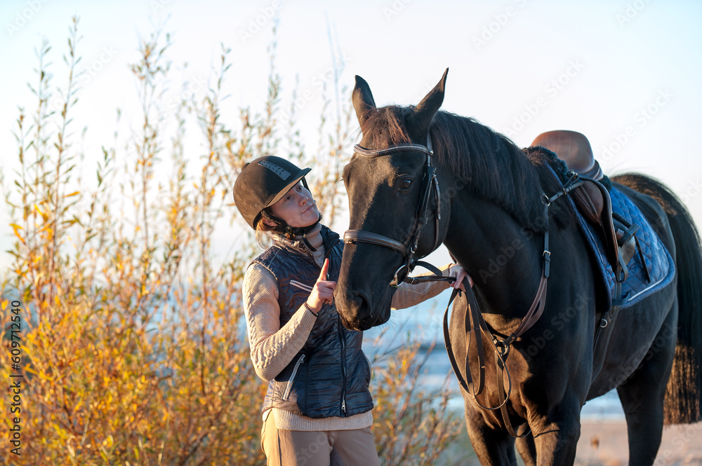 Obraz premium Young smiling Lady standing together with horse on sea beach