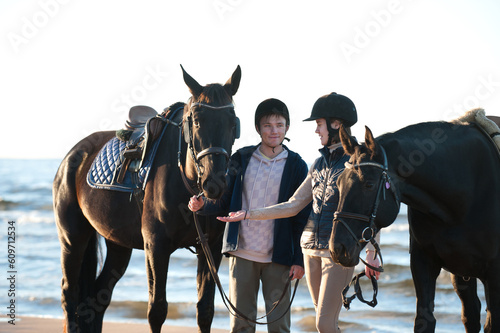 Young couple smiling standing together with horses at wavy sea