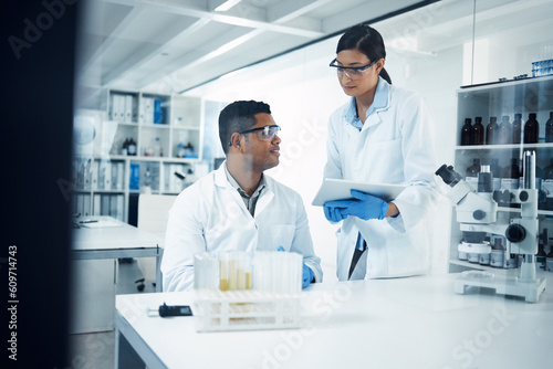 Scientists  tablet and teamwork in research at lab for science data  discovery or results. Man and woman medical professional team working with technology for scientific experiment in the laboratory