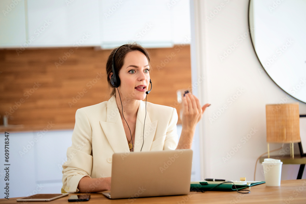 Confident woman with headshet and laptop working at home Confident woman with headshet and laptop working at home