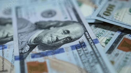 Hundreds of American dollars on table closeup. Camera slowly floats over pile of hundred dollar bills that lie on table, with blurred background in close-up. Paper 100 dollar money cash. photo