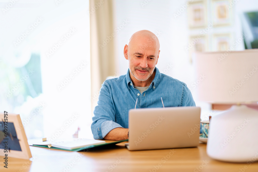 Confident mid aged man using laptop and having video call