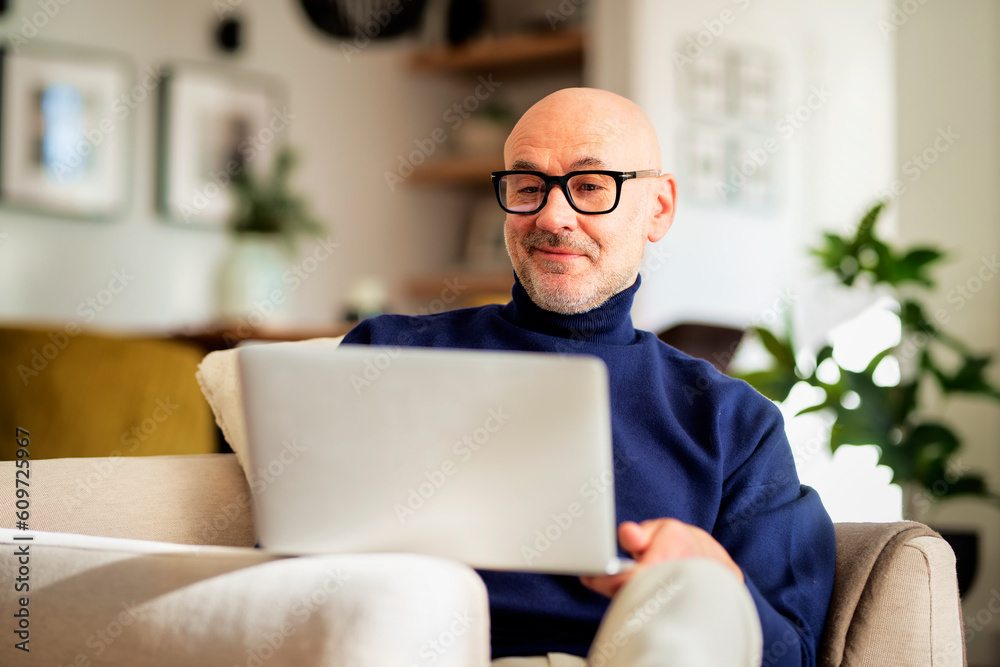 Confident businessman sitting at home and using laptop for work Confident businessman sitting at home and using laptop for work