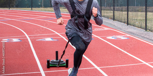 Athlete running while pulling a sled with weight on top photo