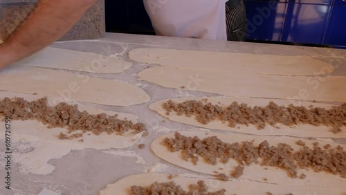 minced meat is placed by hand in to Bafra style pide which is a Turkish pizza with meat in a closed bread