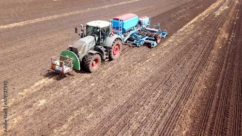 Tractor with a seed drill sowing on a field, farming, aerial view, agriculture, nice birds-eye-view